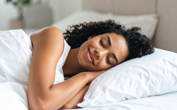 Woman peacefully sleeping in bed, resting on her side with a relaxed expression.